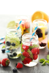 Detox water in bottles with berries on wooden table