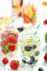 Detox water in bottles with berries on wooden table