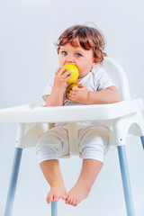 Happy baby boy sitting and eating