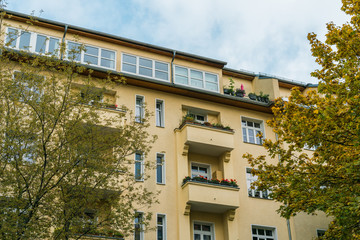 Fototapeta na wymiar orange building with balcony and trees on both sides