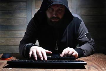 hacker in the black hood in a room with wooden walls