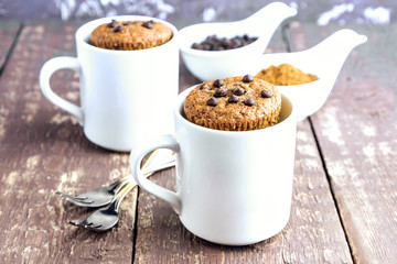 Chocolate muffins with chocolate drops served in white mugs