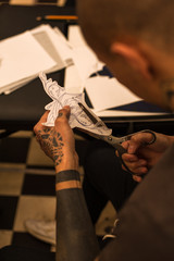 Male tattooer cutting with scissors paper sketch