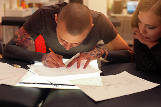 Male tattooer and client creating tattoo sketch