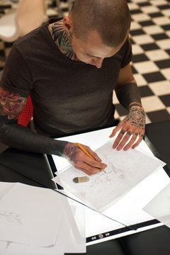 Young tattoo artist creating sketch for client