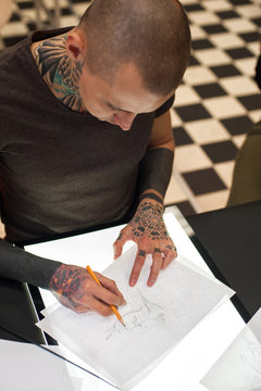 Male tattoo master making sketch for client