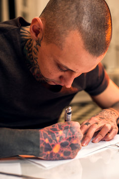 Young male tattooist creating sketch for client