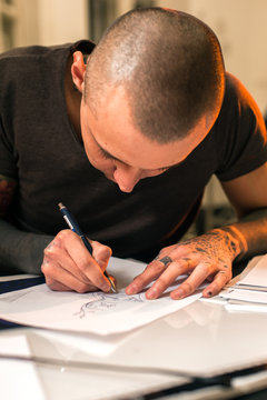 Male tattoo master making desing for tattooing