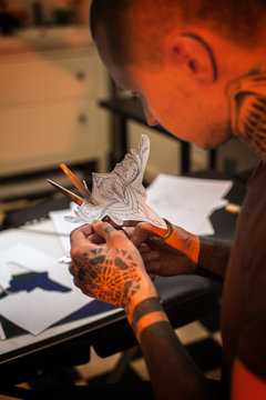 Male tattooer cutting with scissors paper sketch