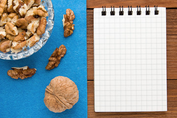 Menu background. Cook book. Recipe notebook with walnuts on a blue background and a wooden board.