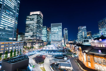 Asia Business concept for real estate and corporate construction - panoramic modern cityscape building bird eye aerial night view of Tokyo Station under neon light and dark blue sky in Tokyo, Japan