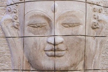 Buddha face carved from a stone wall with stripes