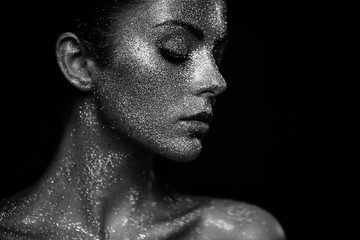Fototapeta premium Portrait of beautiful woman with sparkles on her face. Girl with art make up in color light. Fashion model with colorful make-up. Black and White