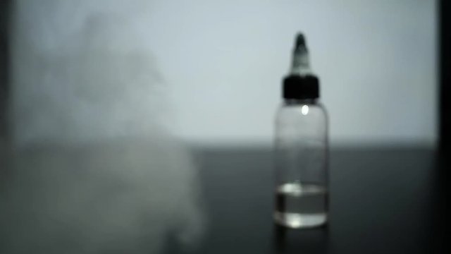 Blur footage. Jar with fluid for electronic nicotine delivery systems and a lot of steam.