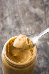 Creamy peanut butter and spoon on wooden background
