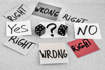 Around black dice are small pieces of paper. On pieces of paper written words and a question mark.
