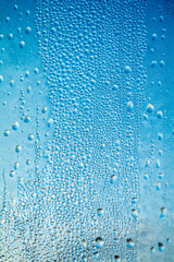 Clear window glass. On the window glass are raindrops.
