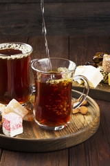 Black tea, oriental sweets, dates and nuts on a dark wooden back