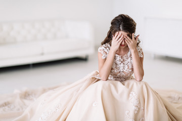 the bride sits in a white room and is sad. Natural light. covers your eyes - 131666955