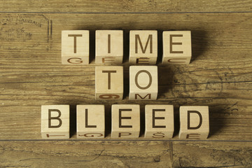 time to bleed text on wooden cubes on wooden background