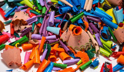 Colorful shavings obtained by sharpening colored pencils, mixed, and on the table.
