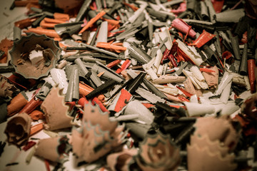 Colorful shavings obtained by sharpening colored pencils, mixed, and on the table.
