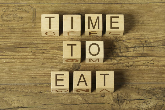 time to eat text on a wooden cubes on a wooden background