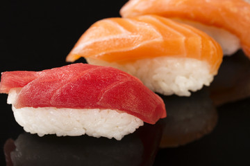 Close-up of Maguro and Salmon sushi on black background with reflection