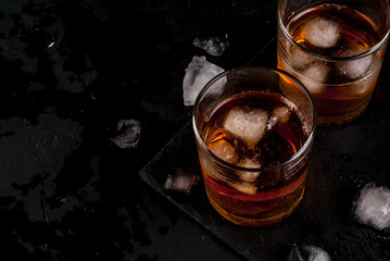 Alcohol whiskey cocktail with cola and ice. On the black table. - obrazy, fototapety, plakaty