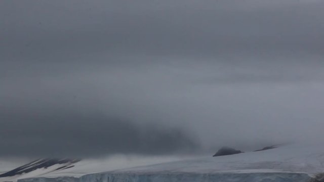 Gloomy Cover glacier in Arctic ( Franz-Josef Land ). Cloud caught on the glacial sheet, nunatak in fog
