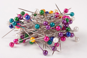 pile of  multi-colored sewing pins on a white background