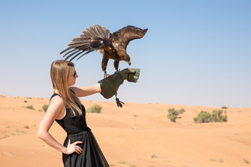 Greater spotted eagle (Clanga clanga) with a beautiful young female model during a desert falconry show in Dubai, UAE.