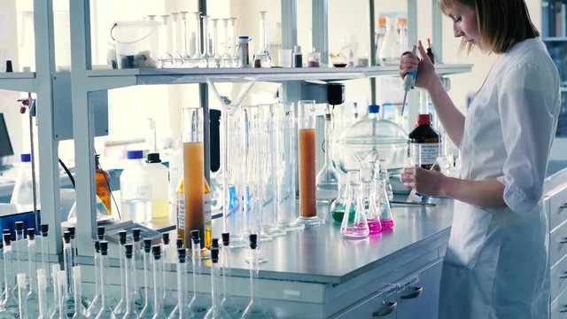 The woman inject dye into a conical flask.