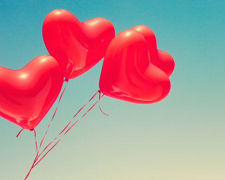 Various red heart shaped balloons in flight