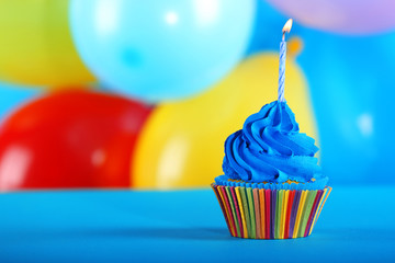 Fresh tasty cupcake with candle on colorful background