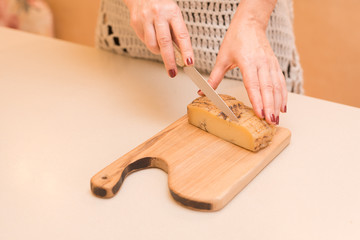 woman cutting cheese on a wooden cooking board