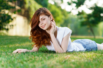 cheerful woman lies in a park on green grass