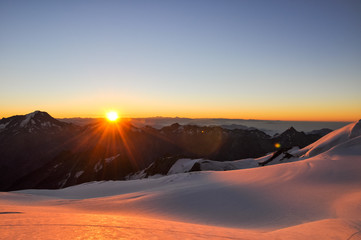 Stunning sunrise at 3800m amsl in the Swiss Wallis Alps near the summit of Alphubel (4206m). Weissmies mountain (4017m) in the background (left side). Snow fields in foreground.