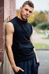 Portrait of a strong handsome man in training cloth. Posing in the hood.