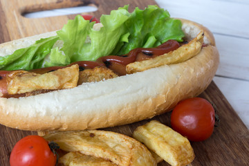 Barbecue Grilled Hot Dog with ketchup, french fries and Cherry tomatoes on wooden background