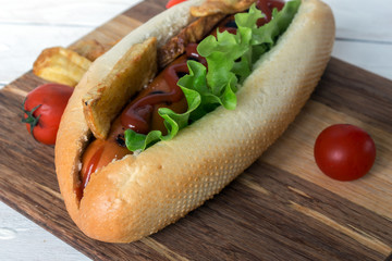Barbecue Grilled Hot Dog with ketchup, french fries and Cherry tomatoes on wooden background