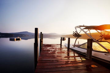 Summer sun rises over a lakeside boat dock