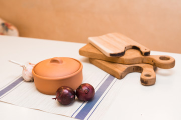 clay pot, garlic and red onions on the table
