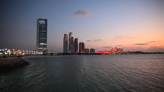 Abu Dhabi skyline at sunset with skyscrapers lit up for the 43rd National day