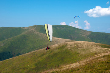 Paraglider flying over the picturesque mountains on a sunny summer day