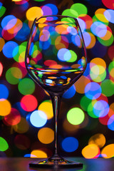 Wine glass on dark multi-colored background