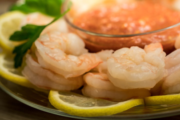 Shrimp cocktail over lemon rounds served with cocktail sauce with parsley sprigs