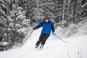Fototapeta na wymiar Skiing Teen in Blue Jacket Spraying Powder 