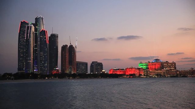 Abu Dhabi skyline at sunset with skyscrapers lit up for the 43rd National day