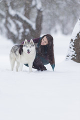 Happy Smiling Caucasian Brunette Woman and Her Husky Dog. Playing with Dog Outdoors